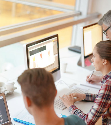 Zwei Lehrnende an Laptops mit Ausbildner